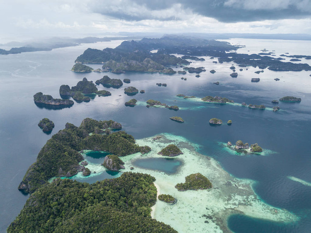 Прочные известняковые острова, найденные недалеко от Мисула, Раджа Ампат, поднимаются из спокойных морей в отдаленной части восточной Индонезии. Этот красивый, богатый природными ресурсами регион известен своим необыкновенным морским биоразнообразием.
. - Фото, изображение