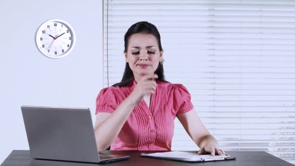 Young female worker working in the office while thinking idea and writing on a paperwork with laptop on desk - Imágenes, Vídeo