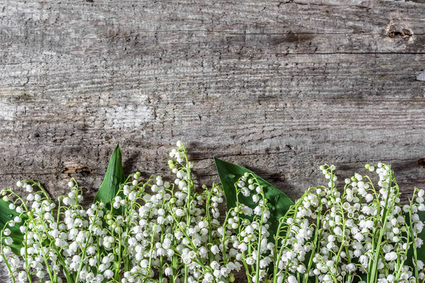 Flores frescas de primavera, ramo de lirios del valle sobre fondo de madera útil como tarjeta de día de la mujer
 - Foto, imagen