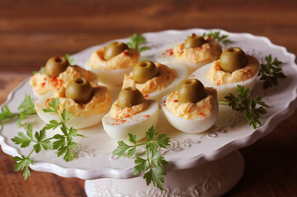 Huevos endemoniados picantes adornados con aceitunas verdes
 - Foto, imagen