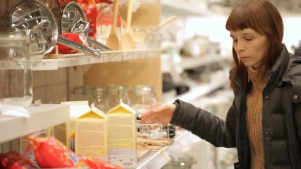Mujer joven está eligiendo la vajilla en la tienda
 - Metraje, vídeo