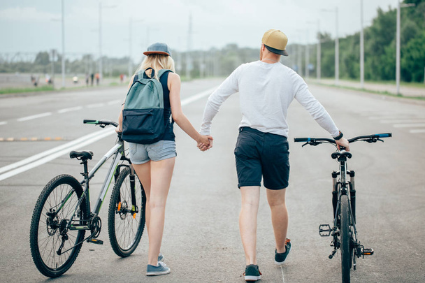 man and woman walk their bikes down the road - Foto, afbeelding