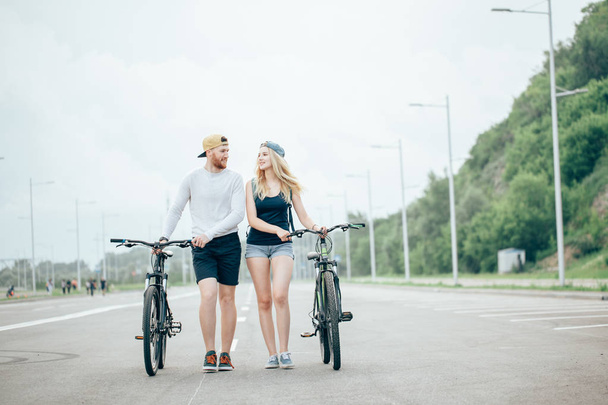 Happy young couple holding hands and riding on bike - Фото, зображення