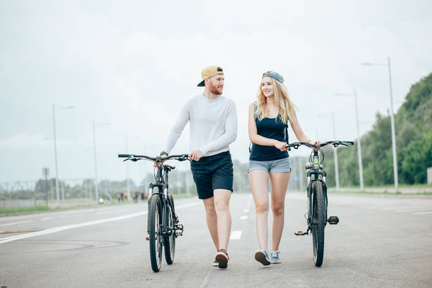 young couple walking bikes together on the road - Foto, immagini