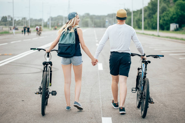 Happy young couple holding hands and riding on bike - Foto, afbeelding