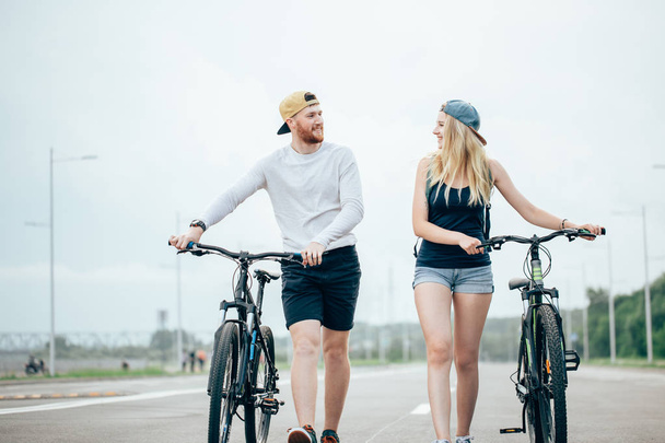 Happy young couple holding hands and riding on bike - Foto, imagen