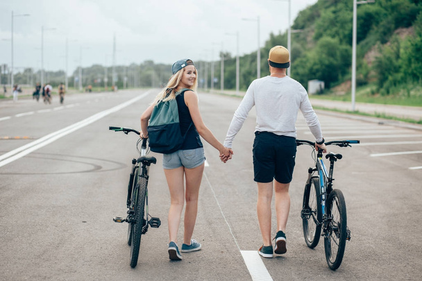 man and woman walk their bikes down the road - Фото, зображення