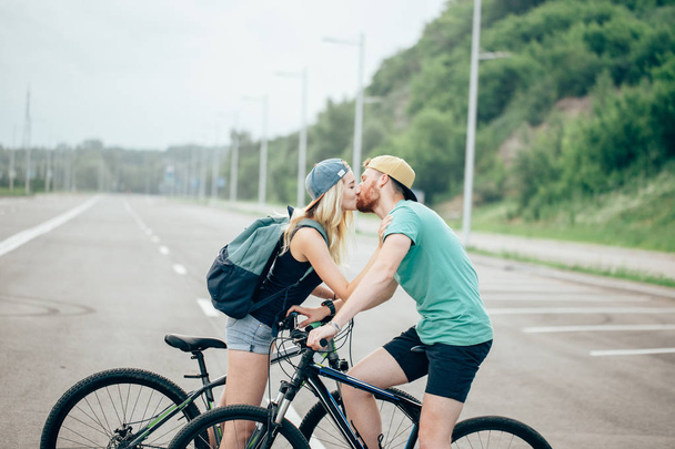 Romantic sports couple kissing against blurred background with bicycles - Фото, изображение