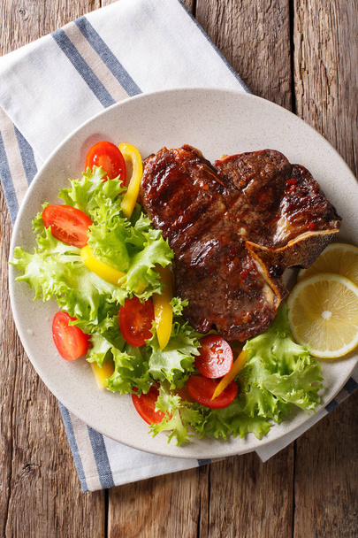 Spicy T-Bone steak with fresh vegetable and lemon close-up. Vert - Photo, Image