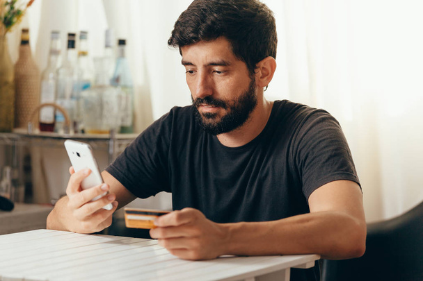 Online payment. Man holding a credit card and using smart phone for online shopping - Φωτογραφία, εικόνα