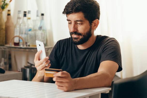 Online payment. Man holding a credit card and using smart phone for online shopping - Φωτογραφία, εικόνα