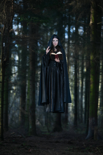 A witch celebrating the spells from the book - Zdjęcie, obraz