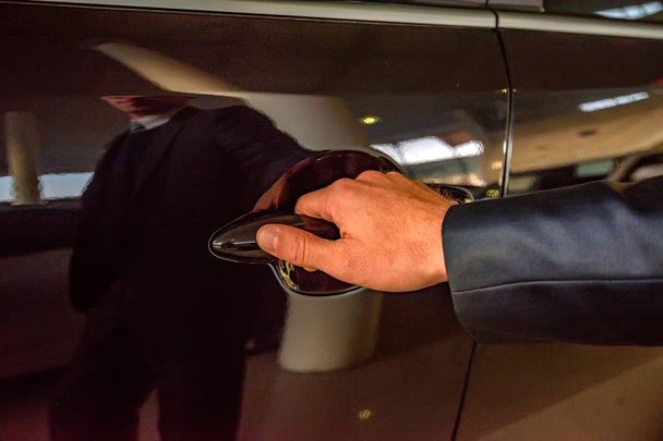 Uomo d'affari mano tenendo auto maniglia della porta
 - Foto, immagini