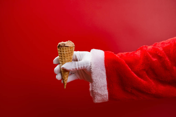 santa claus holding an ice cream cone with some bites on red - Photo, Image