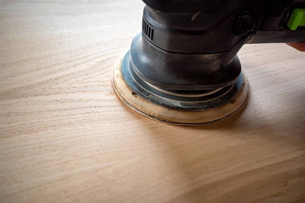 Человек шлифует дрова с орбитальным песком в мастерской
 - Фото, изображение