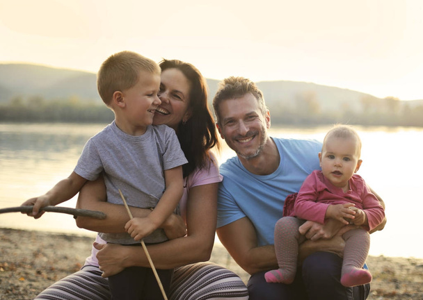 Happy family of four near a lake - Zdjęcie, obraz