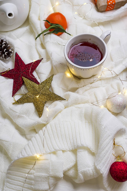 Taza de té caliente con mandarinas y suéteres en la cama
 - Foto, Imagen