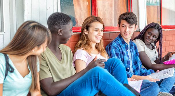 Grupo de adolescentes de razas mixtas en la escuela con cuadernos sonriendo
  - Foto, Imagen