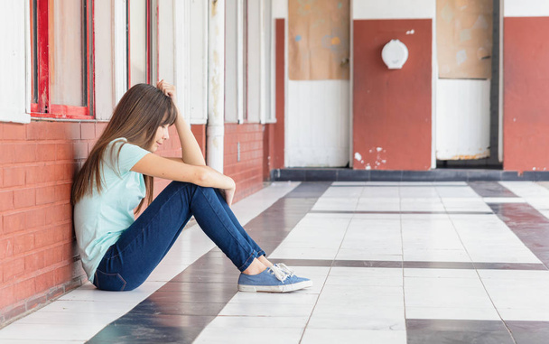 Asiatique adolescent inquiet pour intimidation assis dans le hall de l'école
 - Photo, image