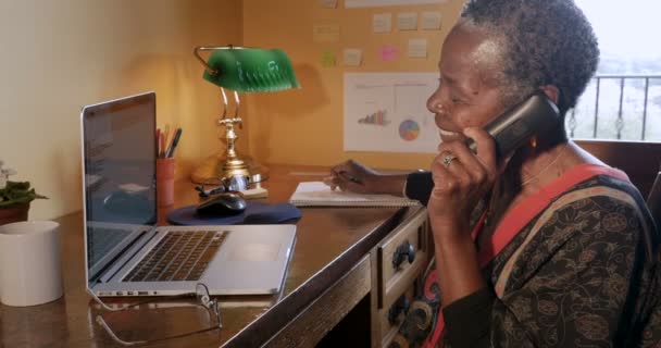Mujer negra madura feliz colgando su teléfono inalámbrico en la oficina en casa
 - Metraje, vídeo