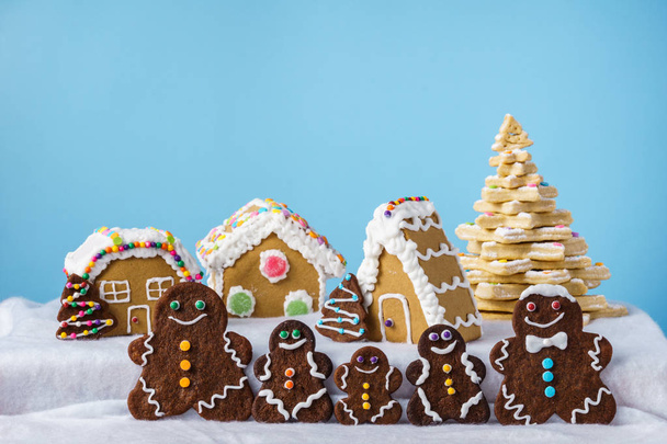 home made delicious traditional gingerbread village and gingerbread man family blue background. - Photo, image