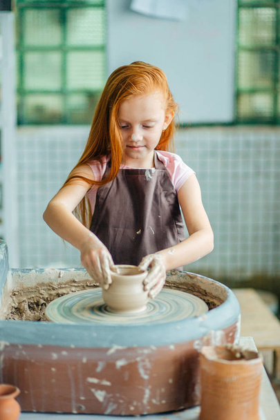 redhead Child sculpts from clay pot. workshop on modeling on potters wheel. - Фото, изображение