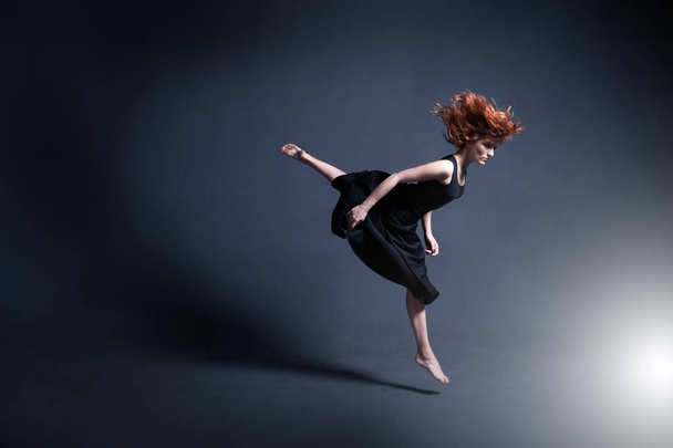 Dancer in a black dress is dancing in the dark studio - Fotoğraf, Görsel