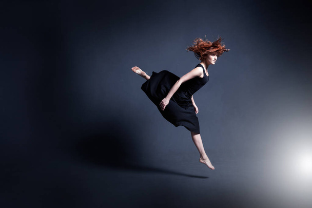 Dancer in a black dress is dancing in the dark studio - Valokuva, kuva