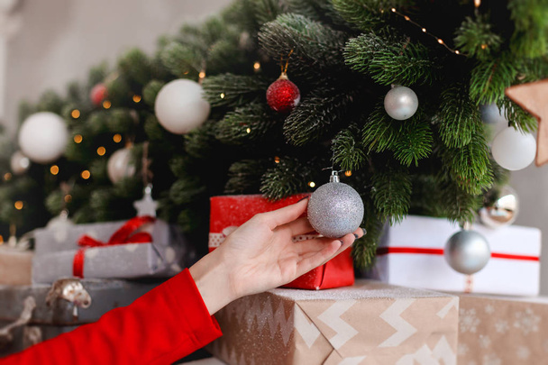 Young woman is decorating the christmas tree in the lovely interior - Fotoğraf, Görsel