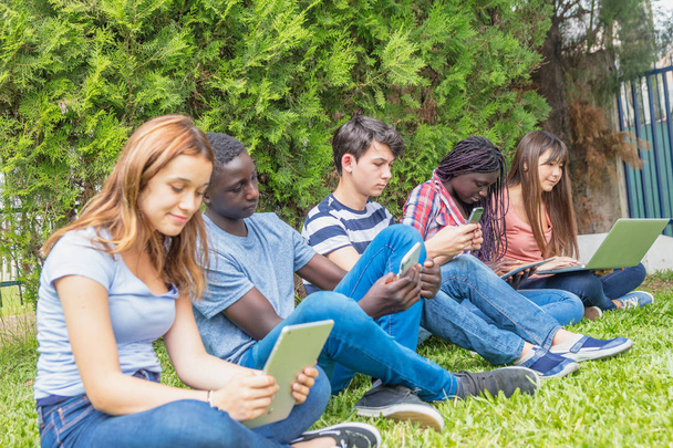 Adolescentes de diferentes razas usando tabletas, teléfonos inteligentes y lapt
 - Foto, Imagen