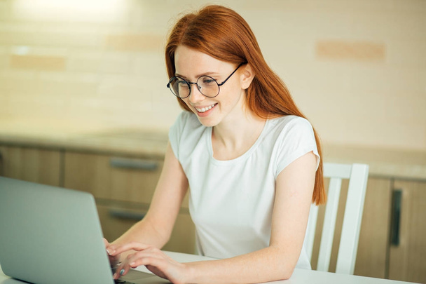 Χαμογελαστή γυναίκα με φορητό υπολογιστή στο γραφείο στο σπίτι - Φωτογραφία, εικόνα