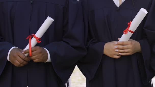 Groep van multi-etnische afgestudeerden bedrijf middelbare school diploma's in handen, gelijkheid - Video