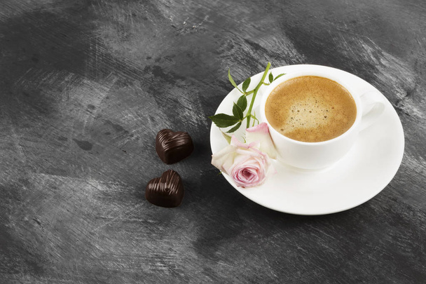 Espresso coffee in a white cup, a pink rose and chocolates on a  - Fotografie, Obrázek