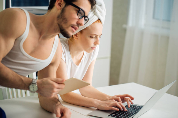 Couple with laptop and tablet in kitchen - Foto, Imagen