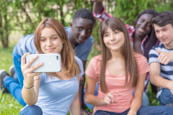 Groupe multi ethnique d'adolescents heureux de faire du selfie sur l'herbe
 - Photo, image