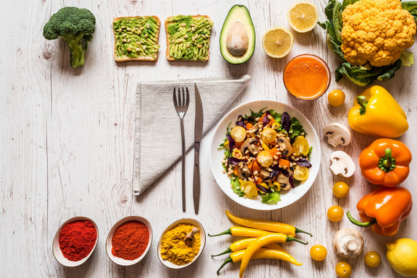 Здорова їжа. овочевий салат, веганські бутерброди з авокадо, морквяний свіжий сік та різні барвисті органічні овочі та спеції
 - Фото, зображення