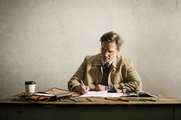 Businessman writing sitting at his desk  - Фото, изображение