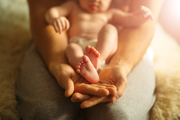 Mother holds newborn babys feets. Tiny feet in womans hand. - Photo, image