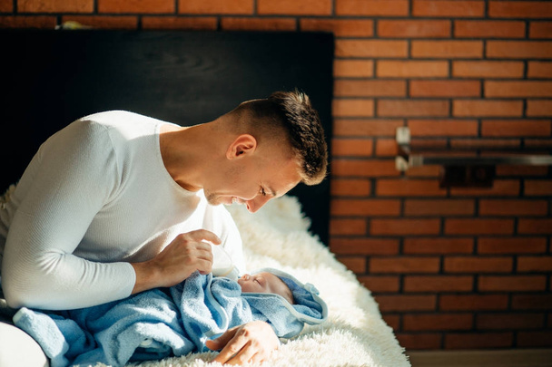 happy father feeding his newborn son with milk in bed at home - Photo, Image