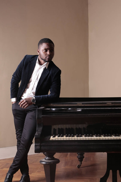 Africano elegante hombre posando cerca de un piano
 - Foto, imagen