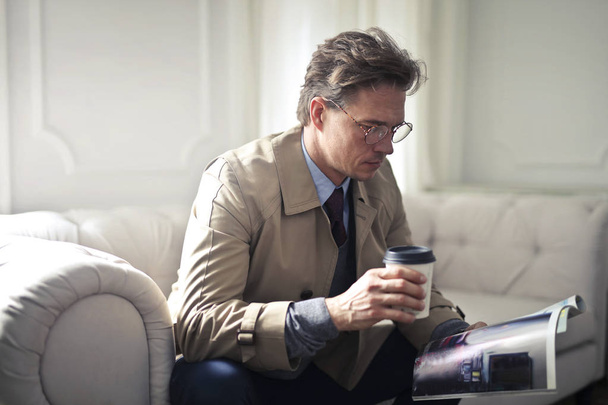 Giovane uomo d'affari elegante leggere una rivista mentre beve un po 'di tè
 - Foto, immagini