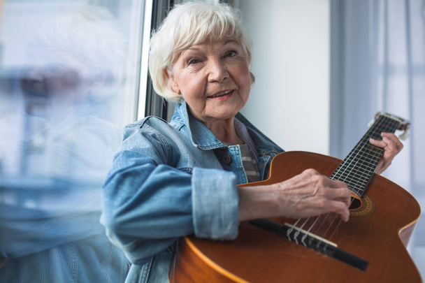 Hurmaava vanha nainen soittaa kitaraa
 - Valokuva, kuva