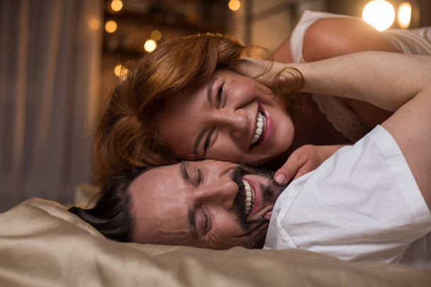 Joyful married couple luxuriating in bed - Фото, зображення