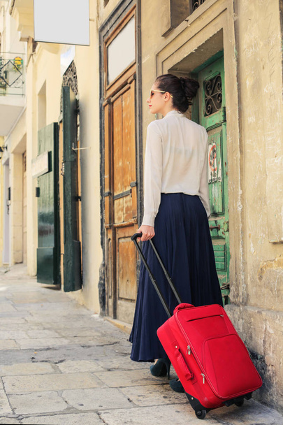 Елегантна жінка, що йде на вулицю з червоним багажем
  - Фото, зображення