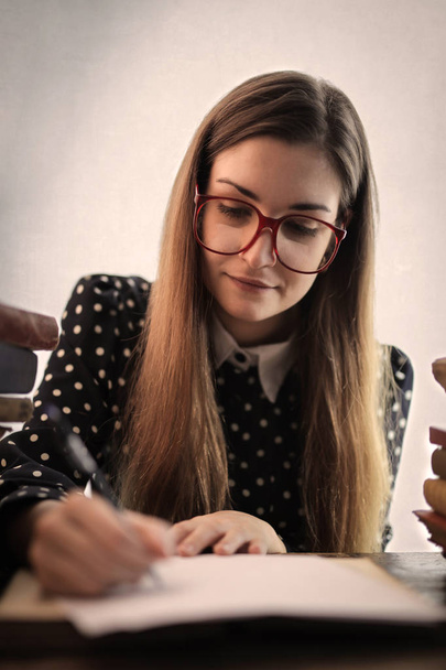 Caucasian student girl with glasses writing a sheet  - Foto, Imagen