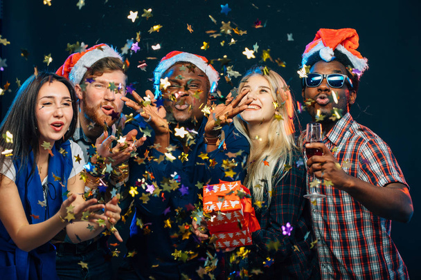 amis à la fête du Nouvel An, portant des chapeaux de Père Noël, dansant et soufflant confettis
 - Photo, image