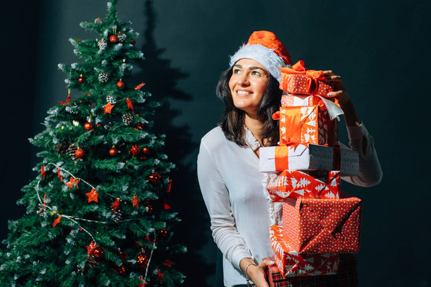 smiling woman in santa helper hat with many gift boxes - Фото, изображение