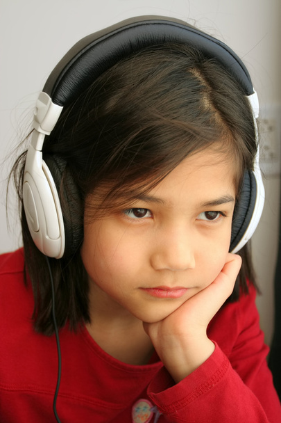 Child with sad expression listening to music with headphones - Zdjęcie, obraz