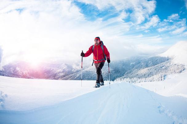 Ένας άνθρωπος με χιονοπέδιλα στα βουνά το χειμώνα.  - Φωτογραφία, εικόνα