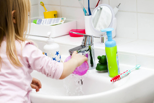 Little girl is brushing her teeth in bath - Fotó, kép